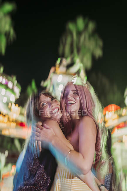 Retrato de duas jovens excitadas abraçando em uma feira à noite — Fotografia de Stock