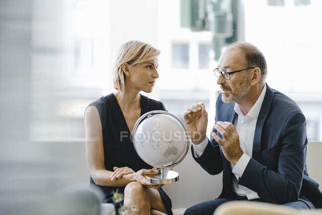 Empresario y mujer sentados en la cafetería, mirando al mundo, discutiendo negocios - foto de stock