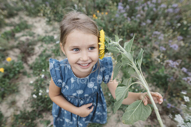Ritratto di ragazza felice con girasole in un campo — Foto stock