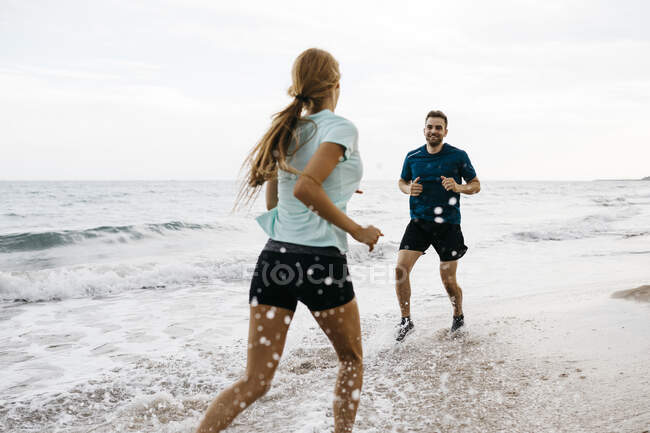 Junges Paar joggt am Strand — Stockfoto
