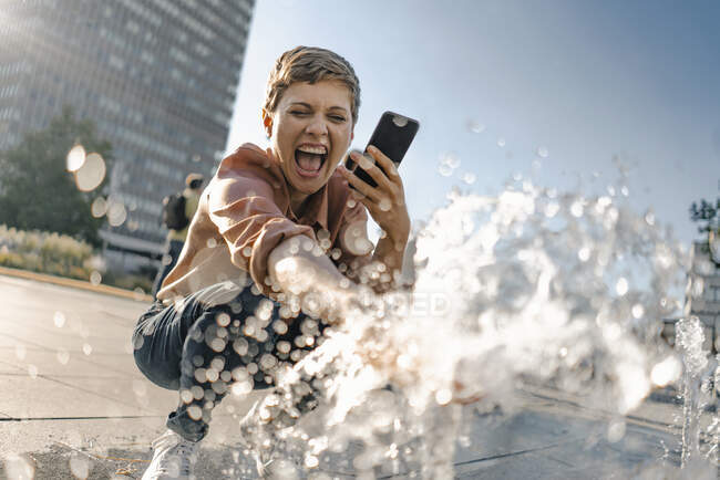 Excited woman at a fountain in the city — Stock Photo