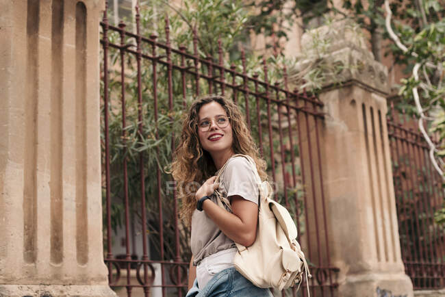 Beautiful young woman with curly hair and glasses in the city — Stock Photo