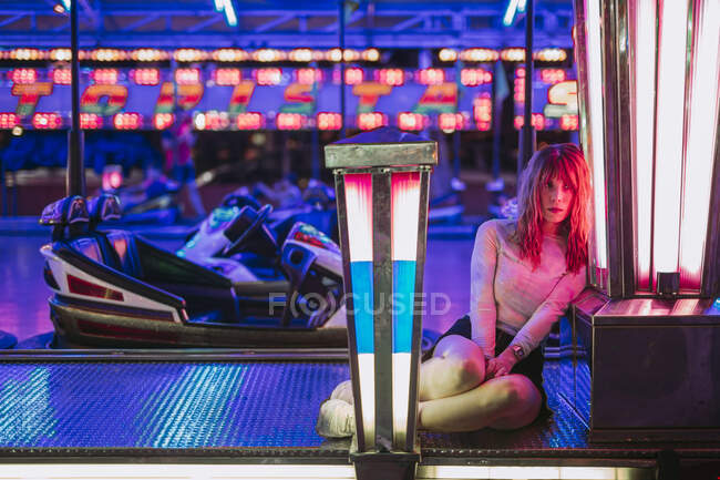 Jovem mulher sentada no carro pára-choques em uma feira à noite — Fotografia de Stock