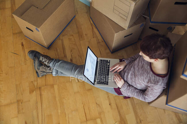Mujer usando portátil con gráfico de línea ascendente en la pantalla en un nuevo hogar - foto de stock