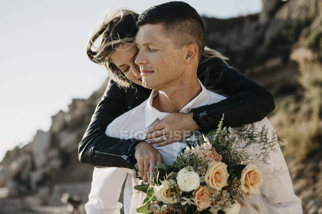 Affettuosa sposa che abbraccia lo sposo sulla costa — Foto stock