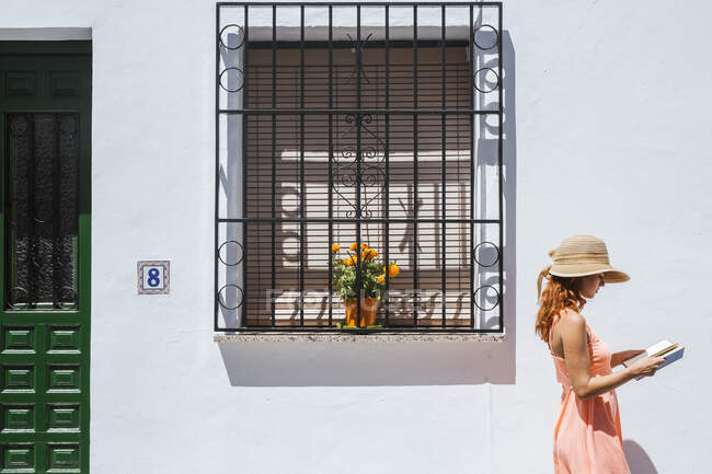 Jeune femme rousse lisant un livre devant une maison, Frigiliana, Malaga, Espagne — Photo de stock