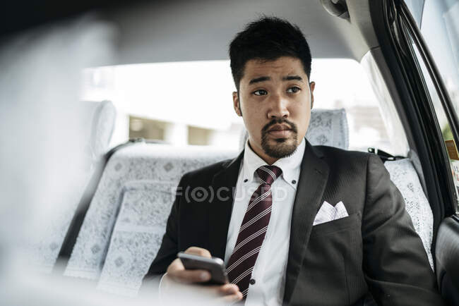 Jeune homme d'affaires avec téléphone portable dans un taxi — Photo de stock