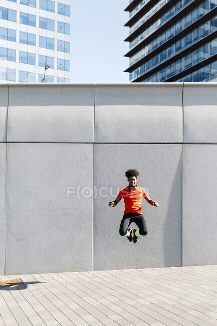 Young man doing jumps with a gray wall in the background — Stock Photo