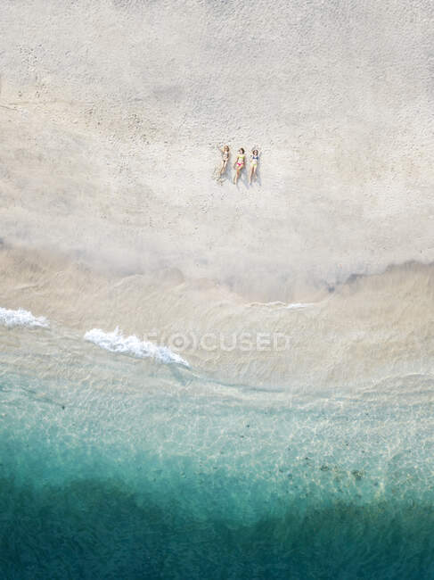 Вид с воздуха на молодых женщин, лежащих на пляже, Gili Air Island, Бали, Индонезия — стоковое фото