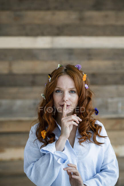 Portrait de femme rousse avec des fleurs dans les cheveux et doigt sur sa bouche — Photo de stock