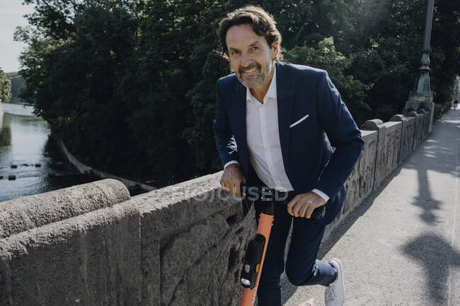 Empresario con e-scooter en un puente - foto de stock