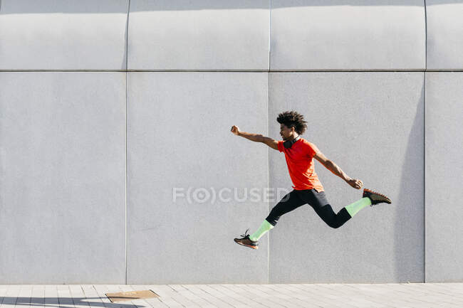 Junger Mann macht Sprünge mit grauer Wand im Hintergrund — Stockfoto