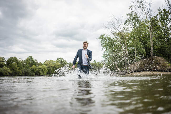 Businessman running through a lake — Stock Photo