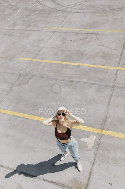 Sorridente giovane donna in piedi su un parcheggio — Foto stock
