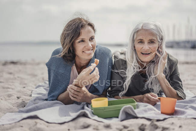 Mère et fille font un pique-nique sur la plage — Photo de stock