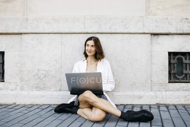 Donna d'affari seduta a terra in città, utilizzando il computer portatile — Foto stock