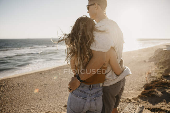 Affettuosa giovane coppia godendo la vista sulla spiaggia al tramonto — Foto stock