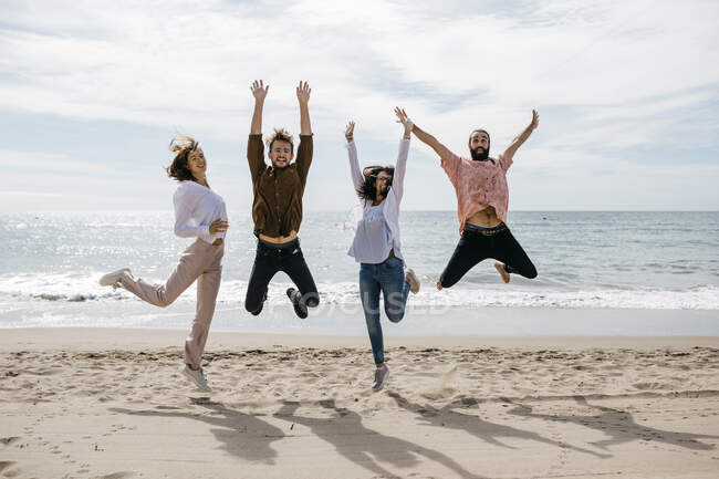 Exuberant friends jumping on the beach — Stock Photo