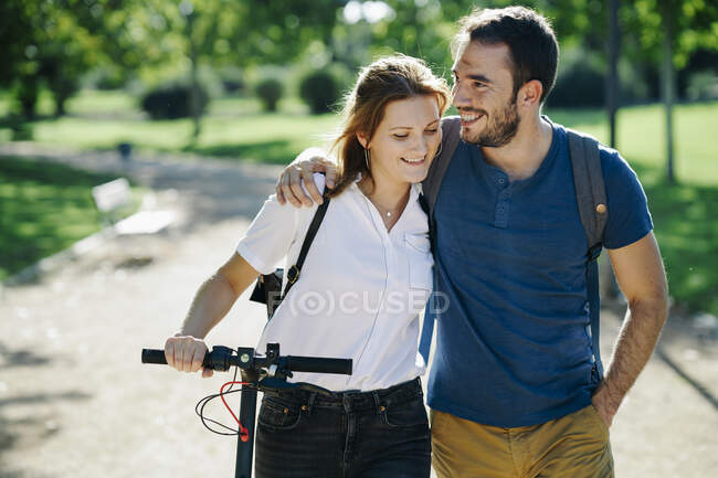 Coppia felice con scooter elettrico in un parco cittadino — Foto stock