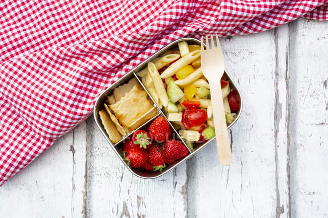 Паста салат, полуниця і крекери в обідній коробці на дерев'яному столі — стокове фото