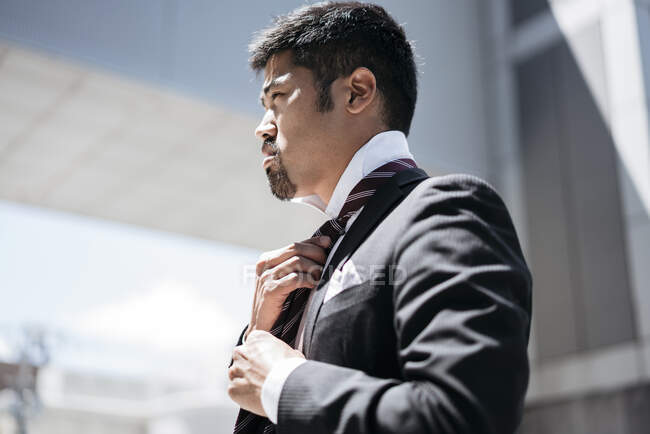 Молодий бізнесмен в місті підлаштовує краватку — стокове фото