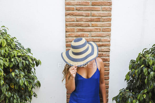 Mulher usando vestido azul e chapéu de palha em pé na frente da parede, Nerja, Espanha — Fotografia de Stock