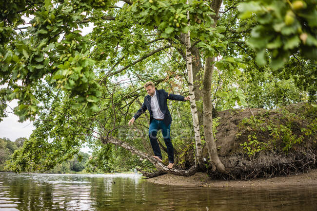 Geschäftsmann balanciert auf Baumstamm über See — Stockfoto