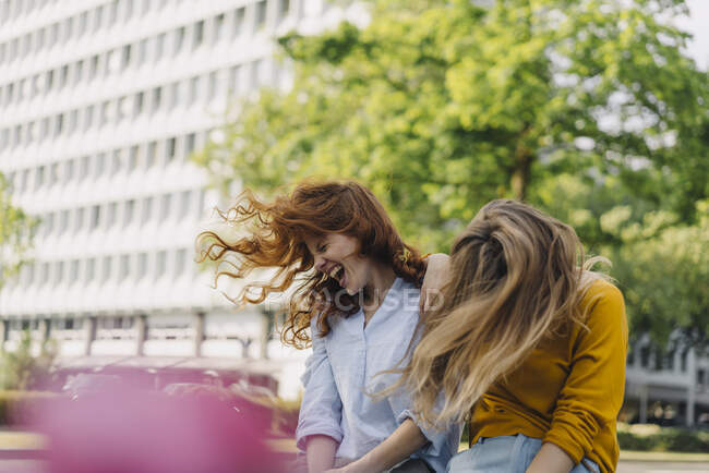 Two exuberant female friends headbanging in the city — Stock Photo