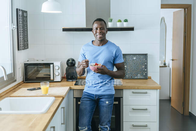 Retrato de un joven desayunando en la cocina de su casa - foto de stock