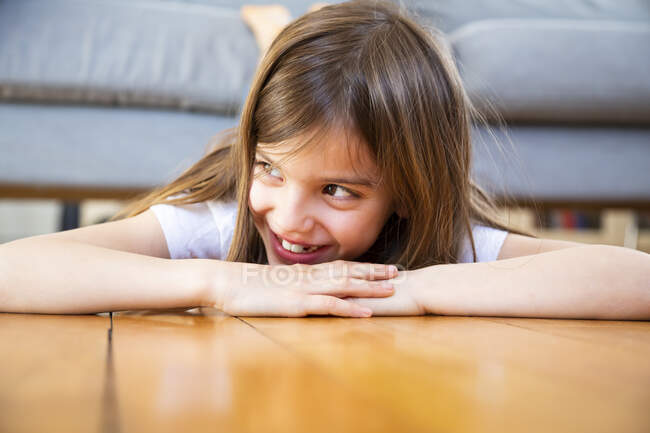 Porträt eines lachenden Mädchens, das zu Hause auf dem Boden liegt — Stockfoto