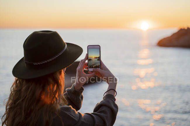 Giovane donna che utilizza smartphone sulla spiaggia durante il tramonto, Ibiza — Foto stock
