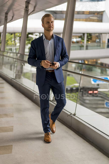 Young businessman on pedestrian bridge — Stock Photo