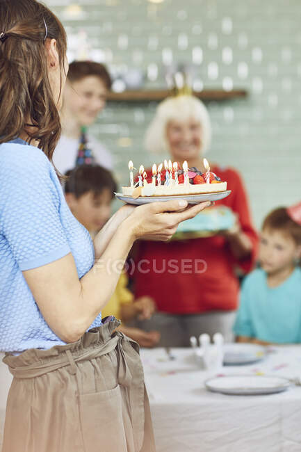 Mother and sons celebrating grandmother's bithday in their kitchen — Stock Photo
