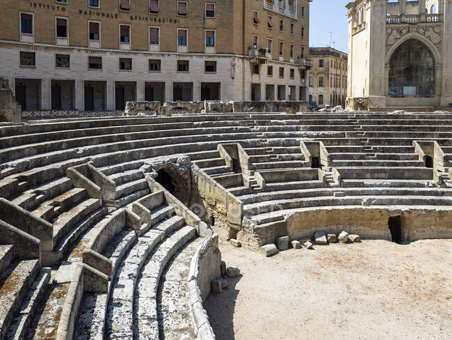 Anfiteatro romano contro edifici ad Altstadt durante la giornata di sole, Lecce, Italia — Foto stock