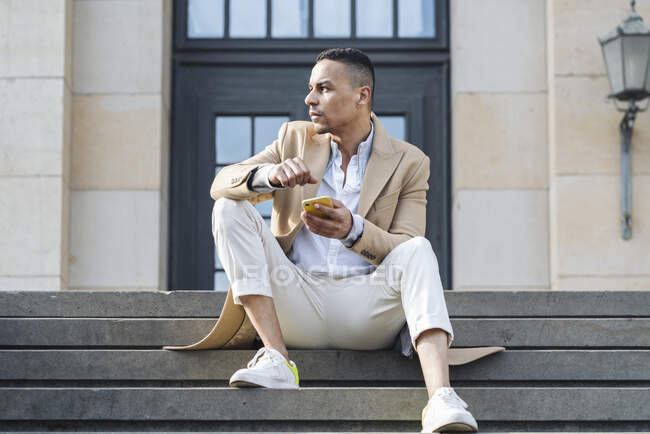 Бізнесмен зі смартфоном, що сидить на сходах у місті — стокове фото