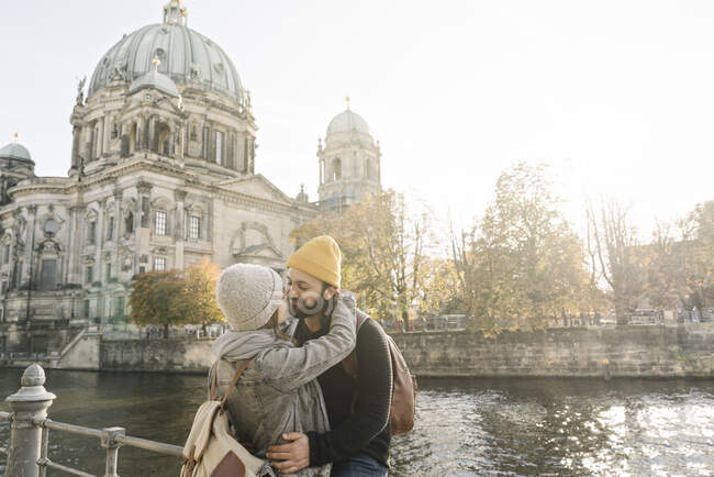 Молодая пара обнимается с Берлинским собором на заднем плане, Берлин, Германия — стоковое фото