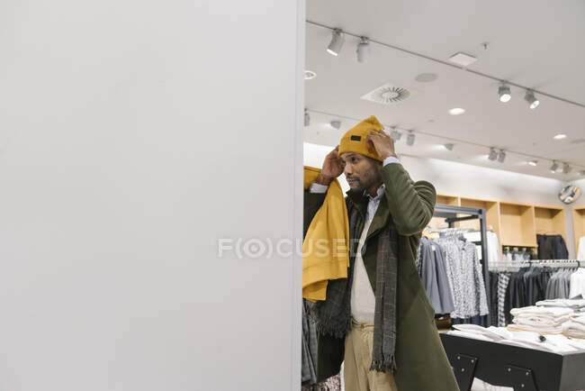Elegante hombre de compras en una tienda de ropa probándose un gorro - foto de stock