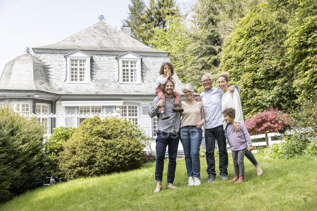 Família estendida feliz que está no jardim de sua casa — Fotografia de Stock