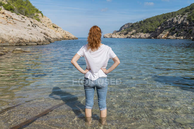Giovane donna in piedi in acqua in spiaggia — Foto stock