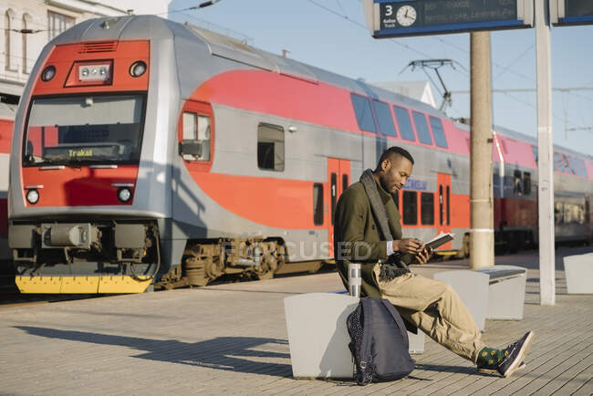 Стильный мужчина читает документы, ожидая поезда. — стоковое фото