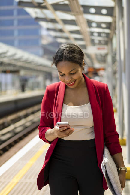 Smiling businesswoman on platform looking at mobile phone, London, UK — Stock Photo