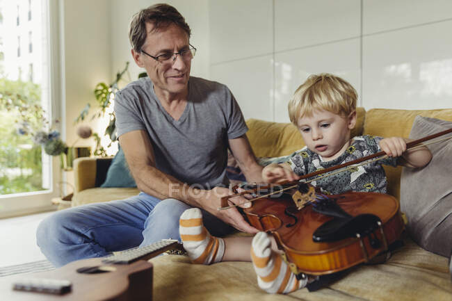 Portrait of toddler testingviolin while his father watching — Stock Photo