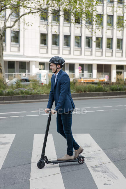 Jeune homme d'affaires équitation e-scooter dans la ville — Photo de stock
