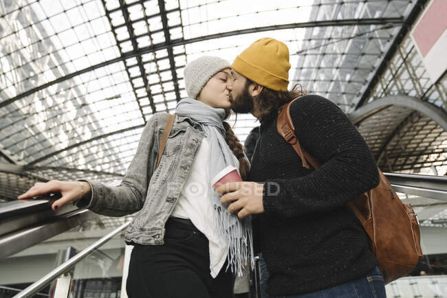 Jeune couple embrassant dans un escalier roulant à la gare, Berlin, Allemagne — Photo de stock