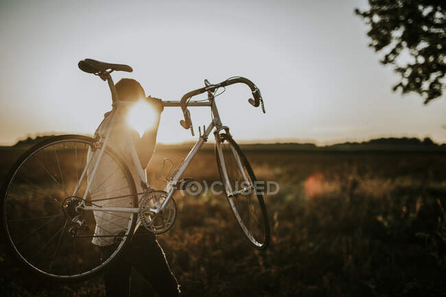 Man carrying a racing cycle in the sunshine — Stock Photo
