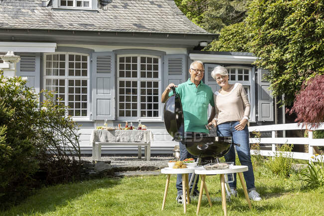 Happy senior couple having a barbecue in garden of their home — Stock Photo