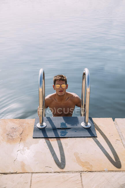 Retrato de um jovem usando óculos escuros saindo da água — Fotografia de Stock
