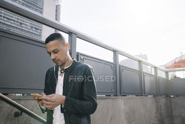 Retrato de homem com fones de ouvido usando smartphone ao sair da estação subterrânea — Fotografia de Stock
