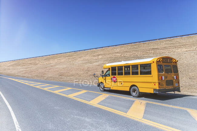 Жовтий шкільний автобус на дорозі до ясного блакитного неба. — стокове фото