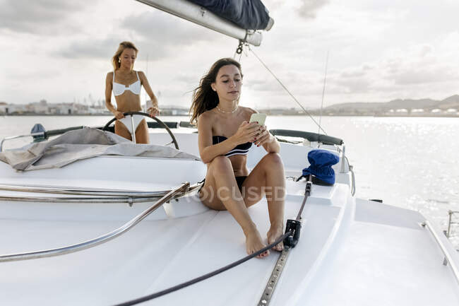 Two beautiful women enjoying a summer day on a sailboat — Stock Photo